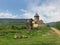 Grand and majestic Hnevank Monastery perched atop a lush, verdant hillside on a sunny day