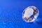 Grand royal pure diamond on blue sparkling sequins background, macro . Big brilliant closeup