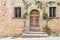 Grand, wooden door graced with green vines in the medieval town of Volpaia.