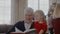 Grandad reading a book with granddaughter, everyone preparing for Christmas Eve