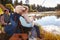 Grandad teaches his grandson to fish at a lake, dad watching