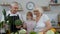 Grandchild girl with senior grandparents recommending eating raw vegetable food. Nutrition diet