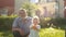 Grandchild and grandfather having fun outdoors. Little boy splashes water from a plastic toy, happy family