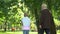 Granddad and grandson walking in park, discussing mens issues, sharing secrets