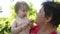 Granddaughter feeds a ripe cherry grandmother in the garden during summer. baby feeding mom red cherry. baby grandmother