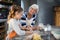 Granddaughter flattening dough with grandmother