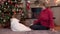 Granddaughter gives grandmother a Christmas present and kisses and hugs her by the tree
