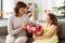 Granddaughter giving grandmother flowers at home