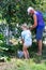 Granddaughter and grandfather pick ripe cherry berries from a tree in the garden on a summer day.