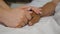 Granddaughter holds and comforts hand of her grandmother in medical clinic. Daughter gently touches wrinkled arm of sick