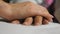 Granddaughter holds and gently strokes hand of her grandmother in medical clinic. Girl comforts wrinkled arm of sick