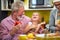 Granddaughter sitting in the lap of a grandpa in the kitchen, laughing together