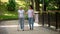 Granddaughter supporting disabled grandma with walking frame, day in park