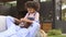 Granddaughter Surprising Grandfather Resting On Seat In Garden At Home