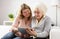 Granddaughter teaching grandmother how to use tablet