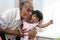 Granddaughter to avoid kiss from her grandfather when enjoying playing a xylophone instrument