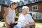 Granddaughter Visiting Grandmother Sitting In Motorized Wheelchair In Retirement Home