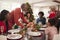 Grandfather bringing the roast turkey to the dinner table during a multi generation, mixed race family Christmas celebration, clos