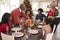 Grandfather bringing the roast turkey to the dinner table during a multi generation, mixed race family Christmas celebration, elev