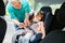 Grandfather Buckling Up On Granddaughter In Car Safety Seat