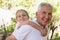 Grandfather carrying granddaughter piggyback in the forest