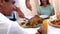 Grandfather carving chicken at dinner table