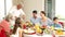 Grandfather carving chicken at dinner table for his family