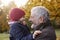 Grandfather Cuddling Granddaughter On Autumn Walk