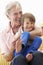 Grandfather Cuddling Grandson On Garden Seat