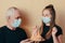 Grandfather in face mask gives a granddaughter a birthday cake with candles,and girl makes a wish. Difficult times and family supp