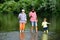 Grandfather, father and son are fly fishing on river. Family bonding. Summer day. Man teaching kids how to fish in river