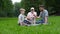 Grandfather, father and son and two dogs Jack russel terrier lying on the green grass in the summer park. Family