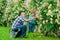 Grandfather and grandchild enjoying in the garden with roses flowers. Cute little boy watering flowers in the summer