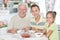 Grandfather and grandchildren eating fresh strawberries at kitch