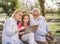 Grandfather And Grandchildren family using laptop while resting in park.