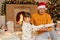 Grandfather and granddaughter reading book near fireplace and xmas tree, grandpa and grandchild with astonished facial expression