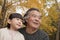 Grandfather and granddaughter smiling and looking away in park