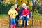 Grandfather, grandmother and two little kid boys, grandchildren sitting in autumn park.