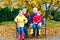 Grandfather, grandmother and two little kid boys, grandchildren sitting in autumn park.