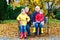 Grandfather, grandmother and two little kid boys, grandchildren sitting in autumn park.