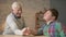 Grandfather and grandson arm wrestle in a cozy room at home. Measuring forces in arm wrestling. Young fat child won