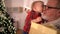 Grandfather and grandson, Christmas portrait. The kid kisses his grandfather on the background of the Christmas tree. A