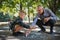 Grandfather with grandson drawing with chalks on pavement outdoors in park.