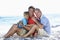 Grandfather With Grandson And Father Embracing On Beach Holiday