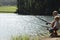 Grandfather And Grandson Fishing By Lake