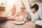 Grandfather, grandson and granddaughter at home. Grandpa is blowing candles on birthday cake.