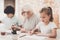 Grandfather, grandson and granddaughter at home. Grandpa is helping children paint.