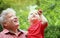 Grandfather and grandson looking on top and smile. Cute toddler boy with his grandfather in summer park