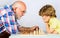 Grandfather and grandson playing chess. Child learning to play chess. Little boy think or plan chess game. Checkmate.