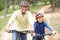 Grandfather and grandson riding bicycle in park